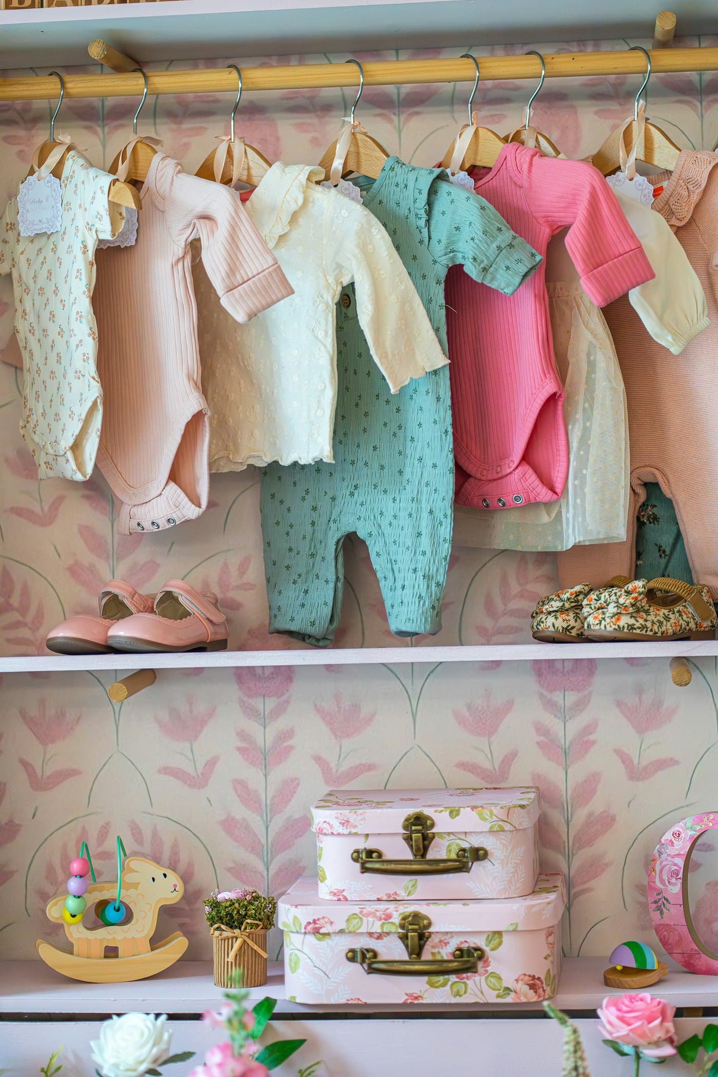 Baby clothing hanging on a rail with shoes and keepsake boxes on shelves